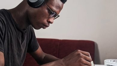 man wearing black crew neck t shirt using black headphones reading book while sitting
