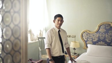 ethnic male maid arranging hotel room
